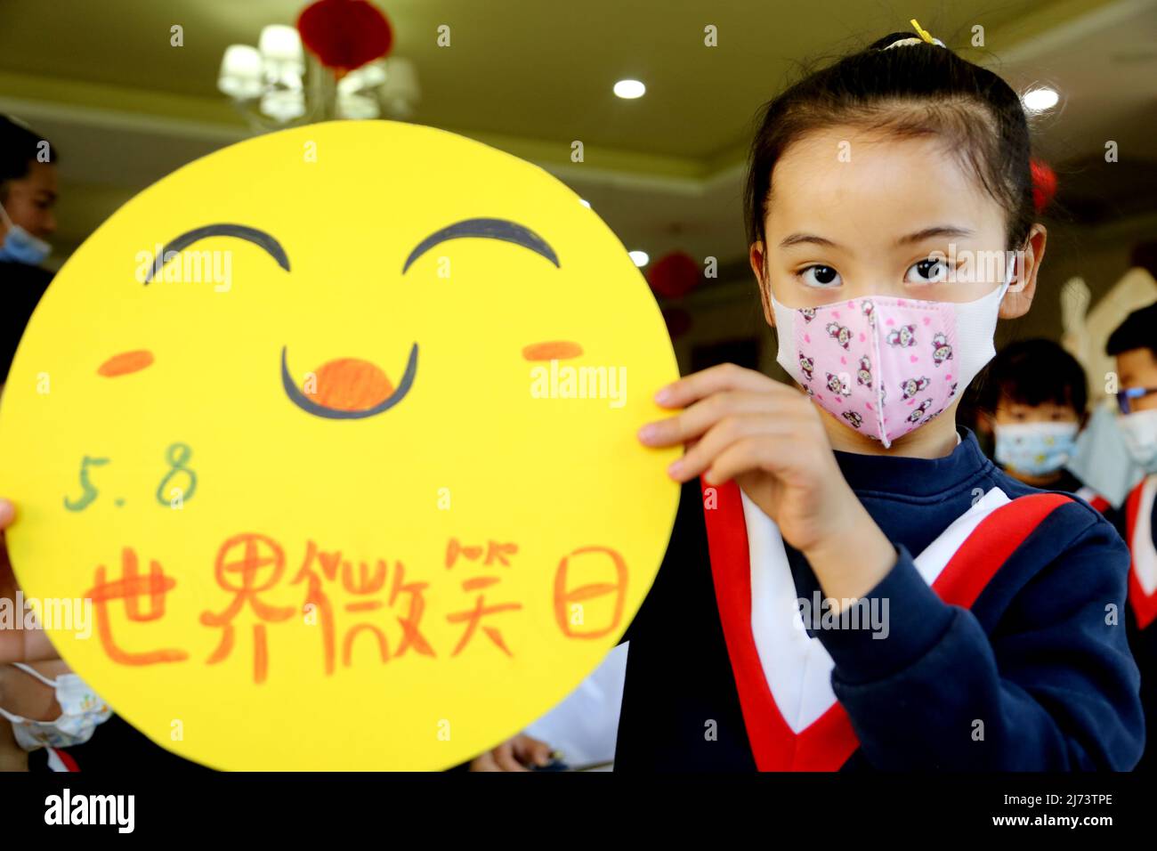 LIANYUNGANG, CHINA - 6. MAI 2022 - Kinder zeigen Bilder von lächelnden Gesichtern im Poly Hele Art Kindergarten in der Stadt Lianyungang, dem Jiangsu Pro in Ostchina Stockfoto