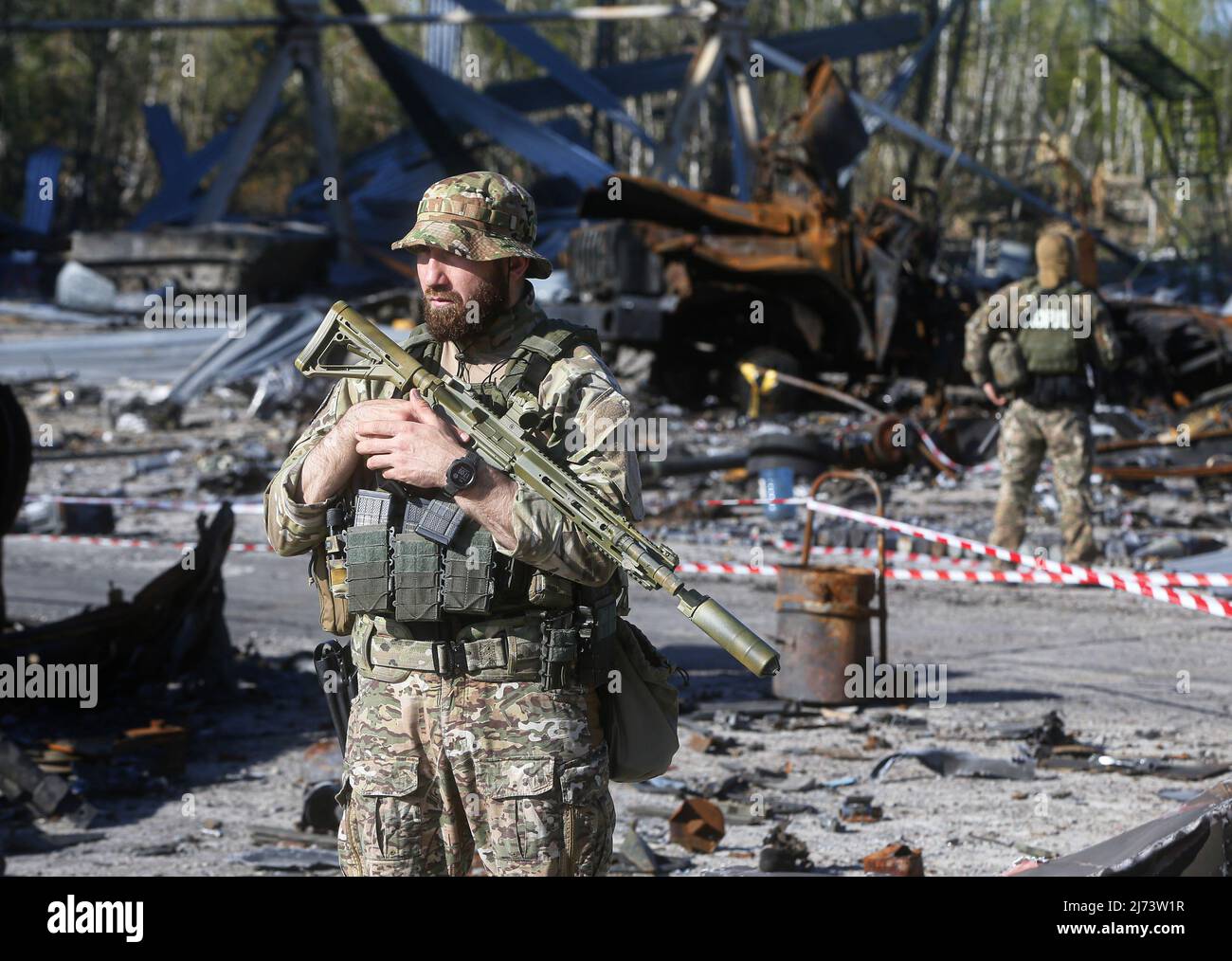 Ukrainische Soldaten stehen nach den Kämpfen mit russischen Truppen auf dem Flugplatz Hostomel vor zerstörten Militärfahrzeugen auf der Wache. Stockfoto