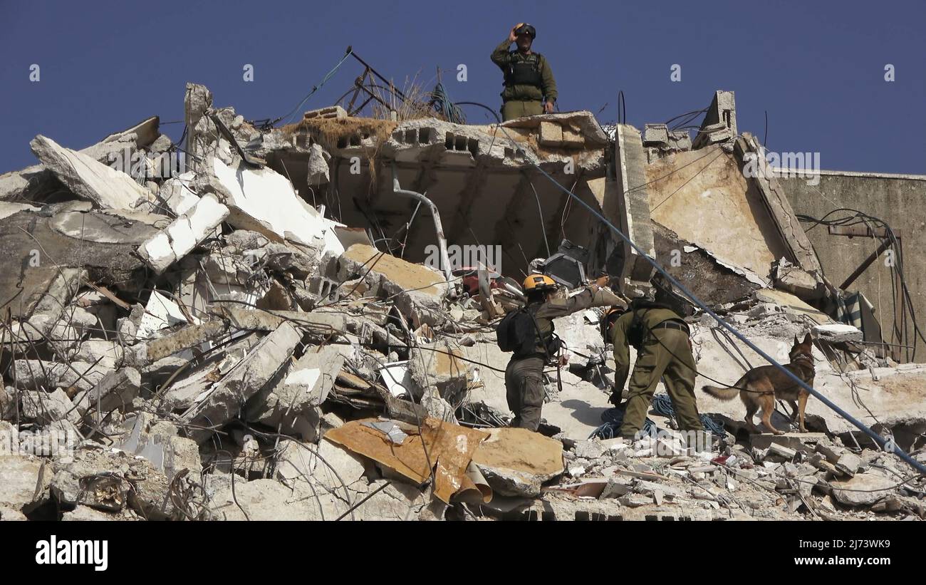 Ein Hundeführer der IDF Oketz Hundeeinheit und ihr Hund gehen durch die Trümmer eines eingestürzten Gebäudes, während israelische Soldaten der Rettungseinheit des Kommandos der Heimatfront am 16. November an einer Such- und Rettungsübung in einem großen Abrissgelände teilnehmen. 2021 in Tel Aviv, Israel. Die Home Front-Übung simulierte Such- und Rettungsaktionen, die sich auf Szenarien vorbereiten, die Gebäude zerstören und Bürger aufgrund eines schweren Erdbebens oder massiver Raketeneinschläge einfangen könnten. Stockfoto