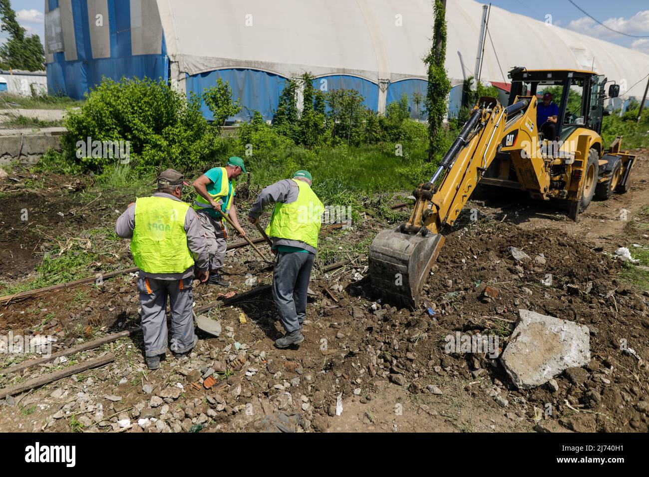 Bukarest, Rumänien - 1. Mai 2022: Arbeiter säubern ein Gebiet von Vegetation und Eisenbahnschutt für zukünftige Bauarbeiten. Stockfoto