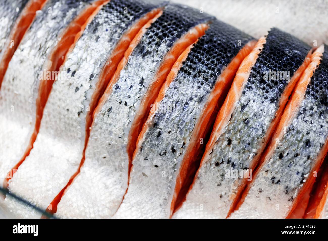 Forelle, in Stücke geschnitten, auf Eis auf dem Ladentisch gelegt. Rote Fischstücke in Nahaufnahme. Stockfoto