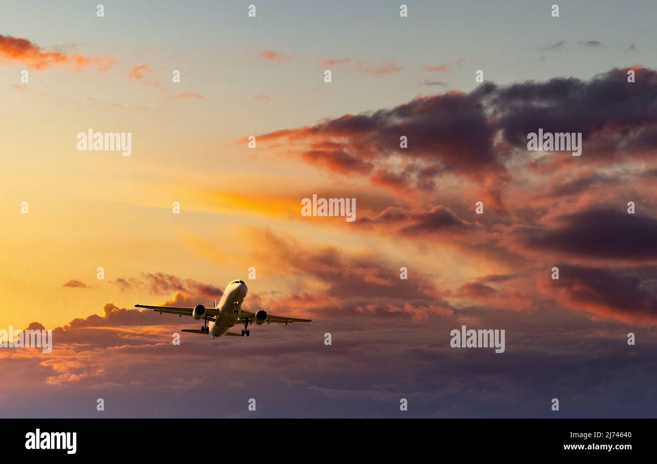 Passagierflugzeuge, die im Abendlicht unter den Wolken fliegen. Stockfoto