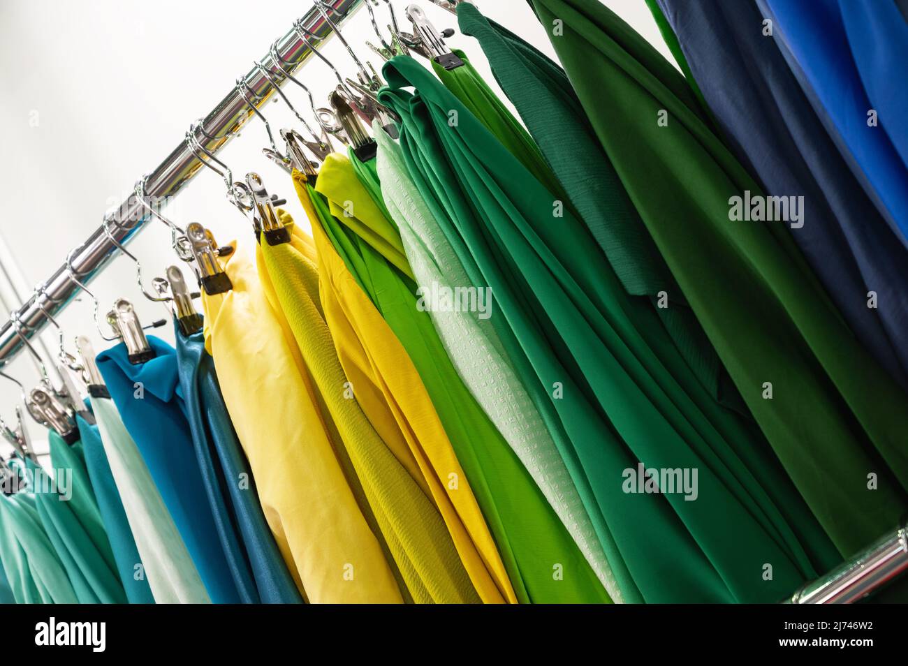 An der Theke hängen Muster von grün-gelben und blauen Stoffen Stockfoto