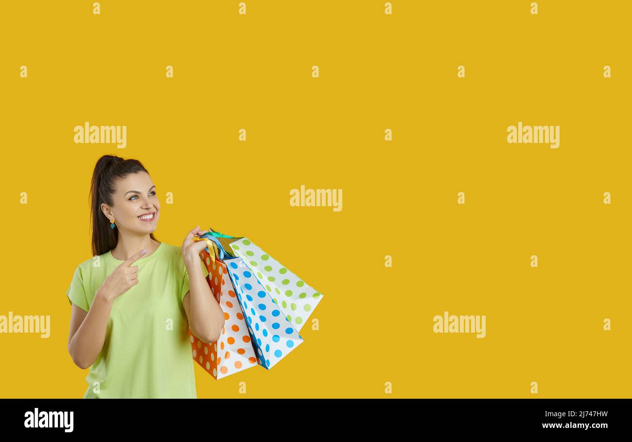 Positive fröhliche Frau mit bunten Einkaufstaschen isoliert auf orangefarbenem Hintergrund. Stockfoto