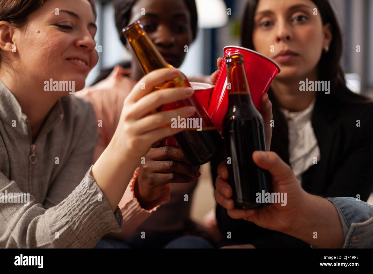 Geschäftsleute klirren nach der Arbeit auf einer Party im Büro auf Gläser und Bierflaschen. Freunde treffen sich, um nach der Arbeit einen Drink zu genießen und feiern mit Jubel. Nahaufnahme. Stockfoto