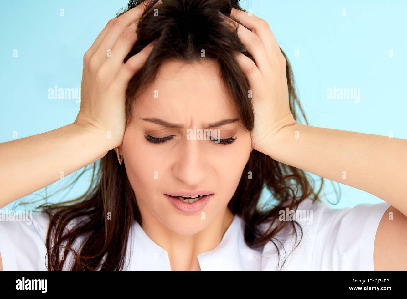 Kopfschmerzen und Stress. Schöne junge Frau Gefühl starker Kopf Schmerzen. Portrait von Müde betont Weibliche Leiden unter schmerzhaften Migräne, halten sich an den Händen Stockfoto