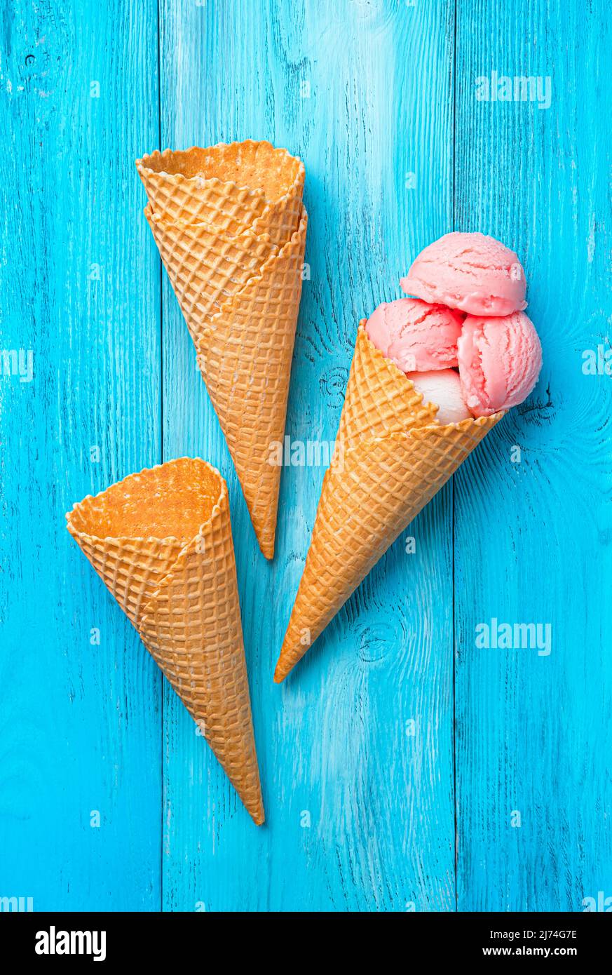 Beere und Sahneeis und Waffelbecher auf blauem Hintergrund. Stockfoto