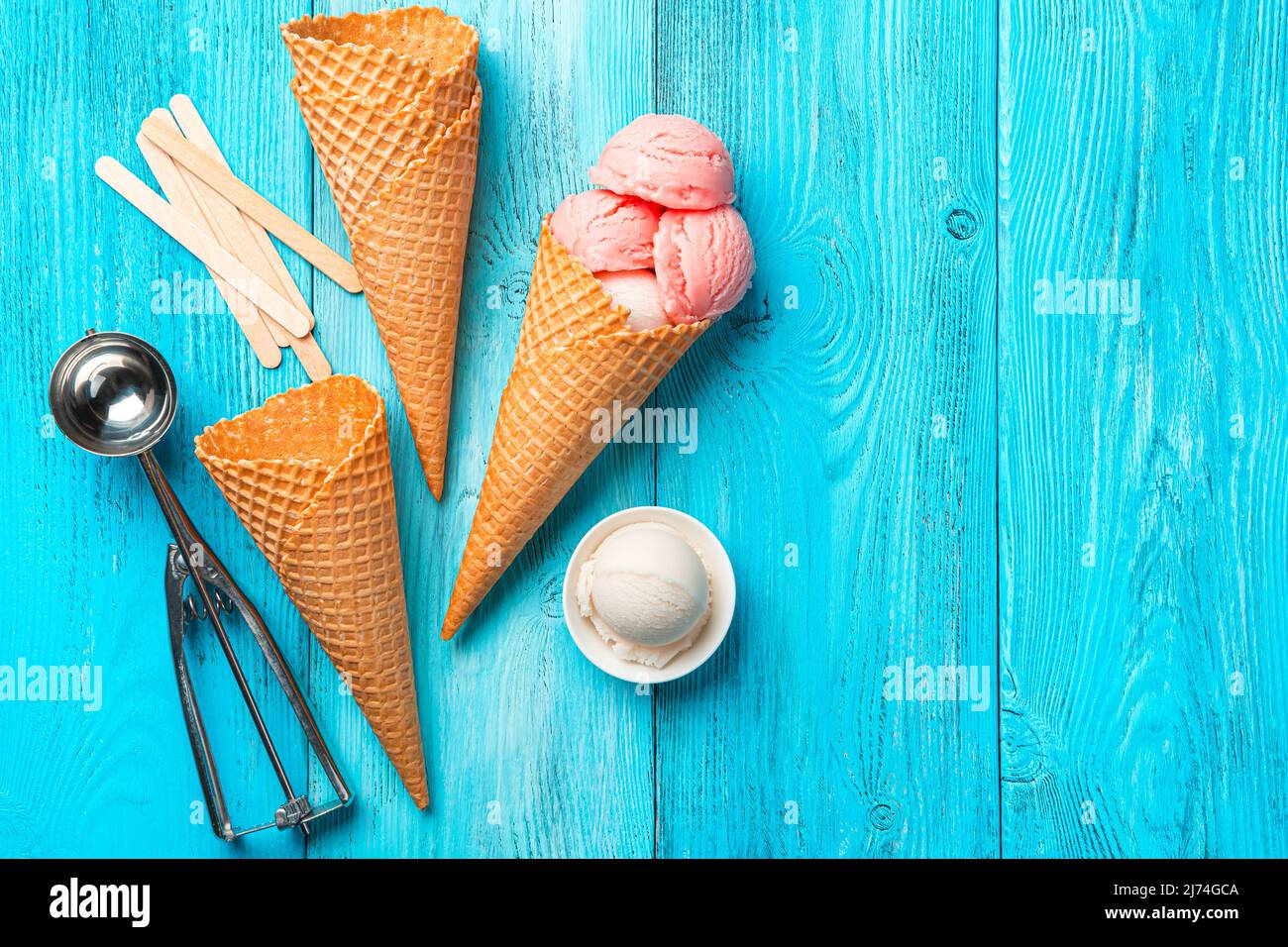 Beereneis, Waffelbecher und ein Löffel auf blauem Hintergrund. Stockfoto