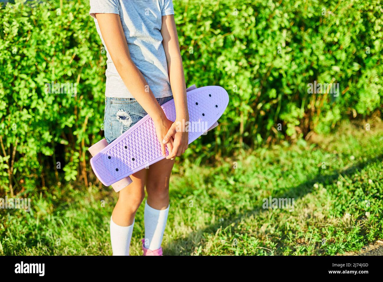 Das kleine Mädchen hält ein Skateboard, ein anonymes Kind trägt weiße  Socken und pinkfarbene Schuhe und reitet auf einem Skateboard auf einer  ländlichen Straße der Sommerstadt Stockfotografie - Alamy