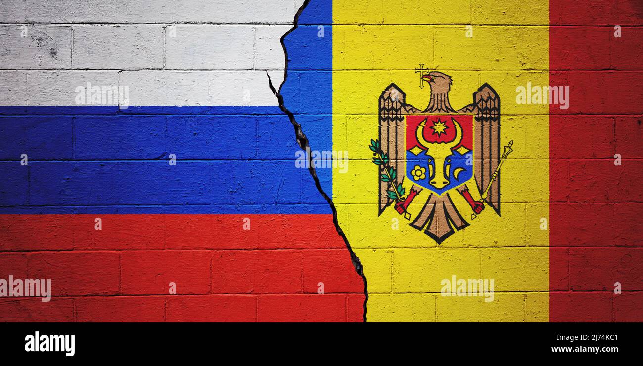 Rissige Ziegelwand mit einer russischen Flagge auf der linken Seite und einer Flagge der Republik Moldau auf der rechten Seite bemalt. Stockfoto