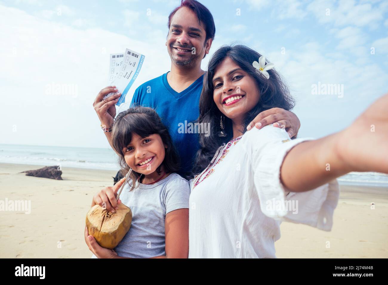 Junge indische Familie entspannt sich und nimmt Selfie auf Kamera-Smartphone mit Ticket und Kokosnuss in Goa Stockfoto