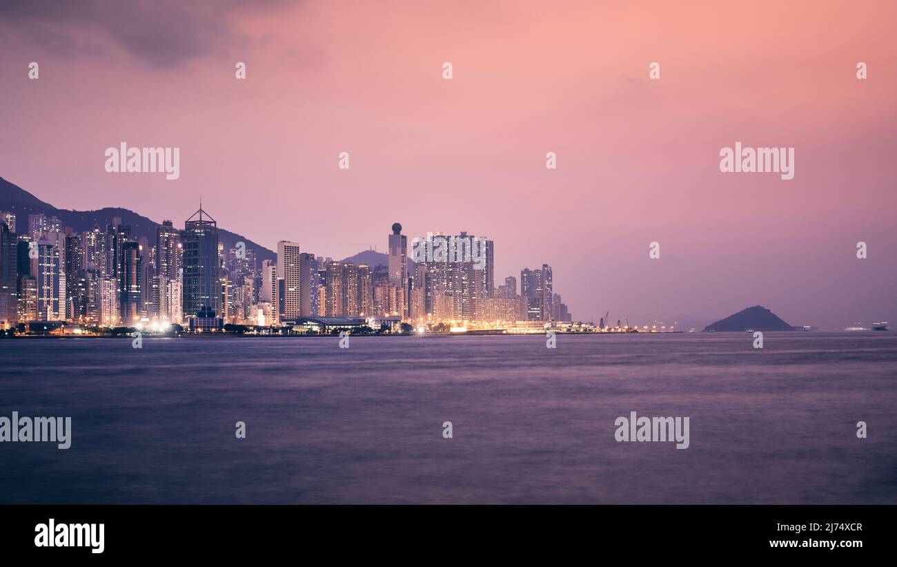 Städtische Skyline mit beleuchteten Wolkenkratzern in der Dämmerung. Stadtbild von Hongkong. Stockfoto