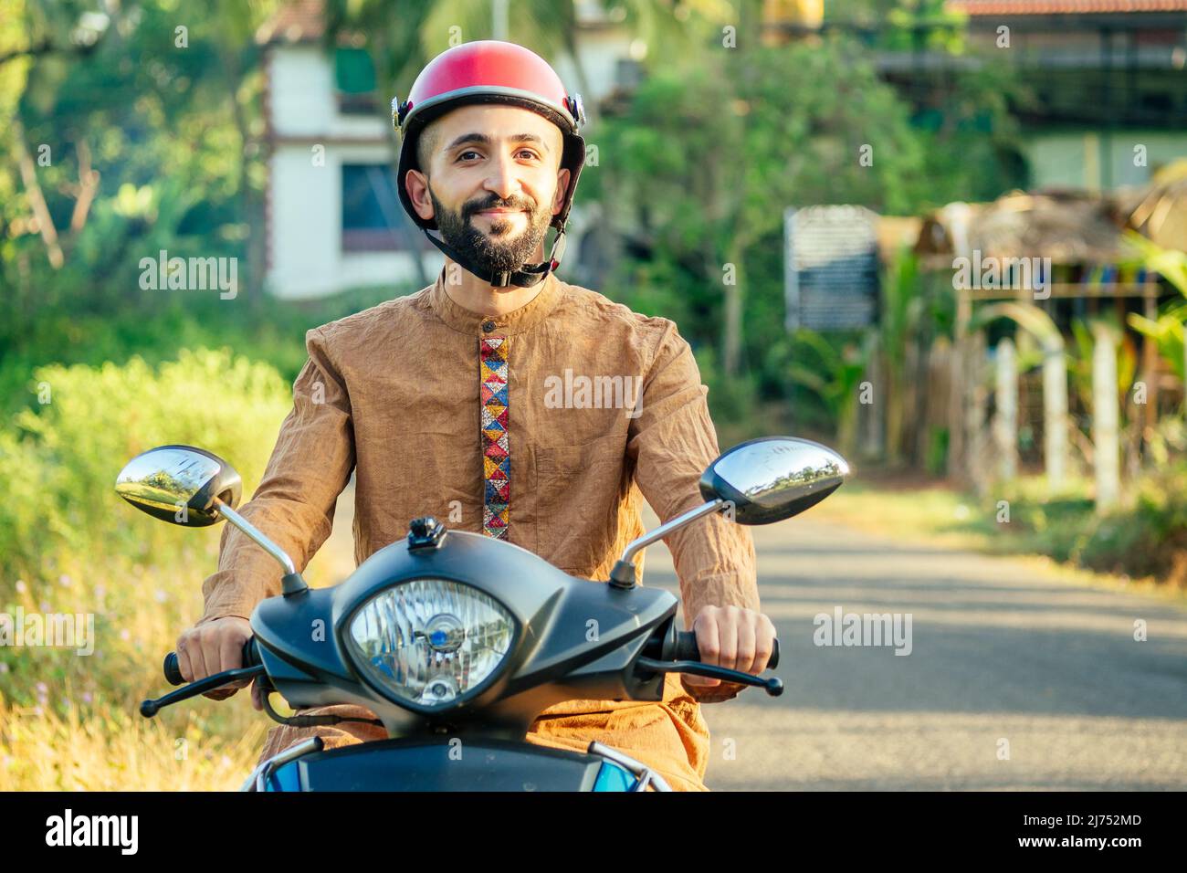 der indische Mann trägt Helm und ist bereit, die indischen Attraktionen von Goa zu erkunden Stockfoto