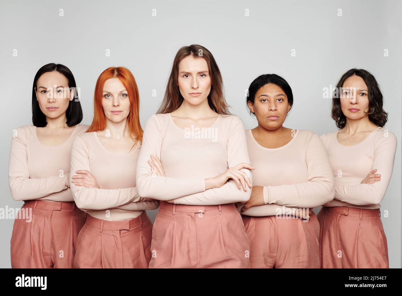 Porträt von seriös selbstbewussten Frauen verschiedener Rassen, die mit gekreuzten Armen vor isoliertem Hintergrund stehen Stockfoto