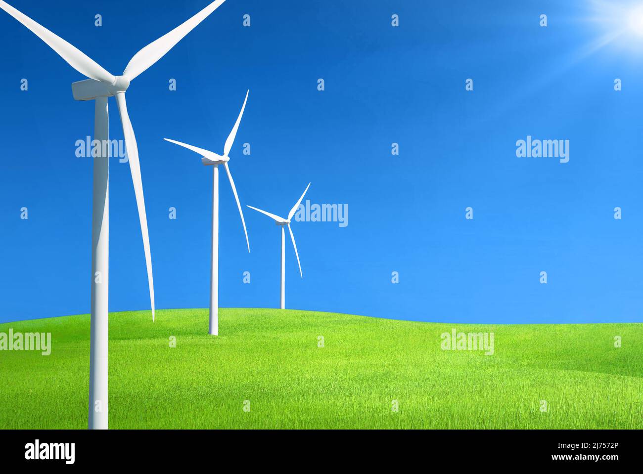 Reihe von Windgeneratoren in einer Reihe auf einem Hügel aus grünem Gras gegen tiefblauen Himmel mit Sonnenlicht Stockfoto