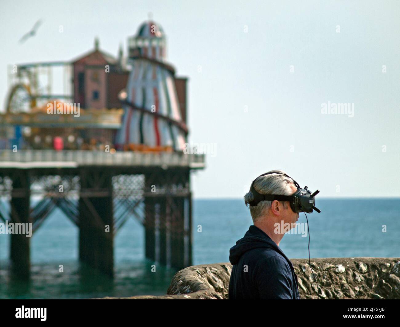 Ein Mann trägt ein VR-Headset an der Strandpromenade von Brighton Stockfoto
