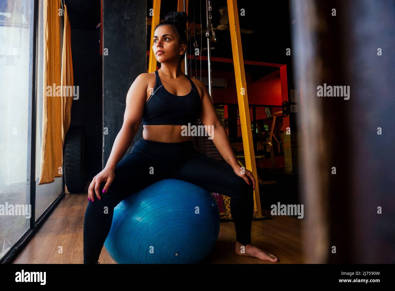 indische Frau macht Pilates und Balance-Übungen Gymnastikball Stockfoto