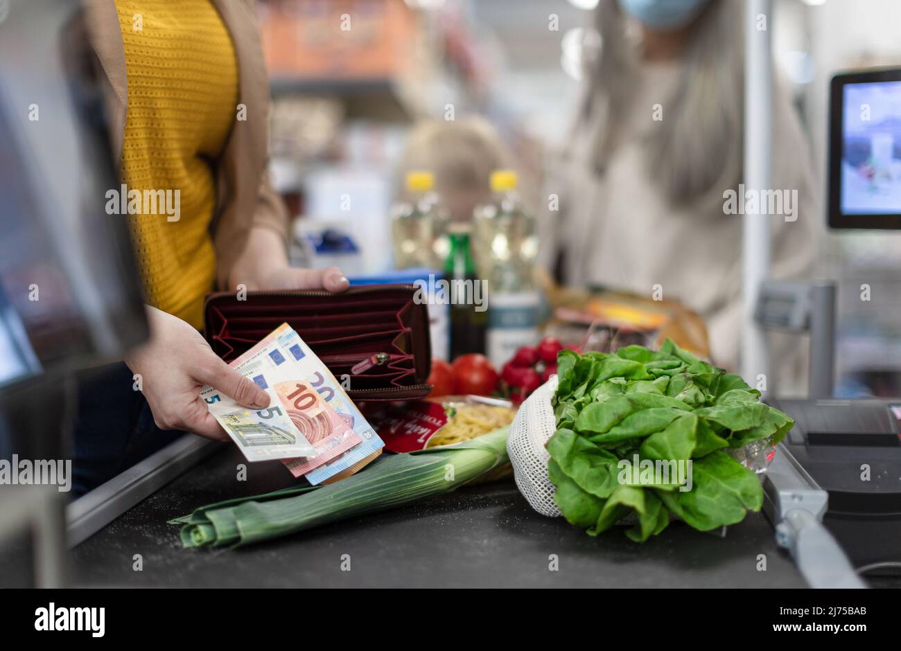 Nahaufnahme einer Frau, die Geld an der Kasse im Supermarkt gibt Stockfoto