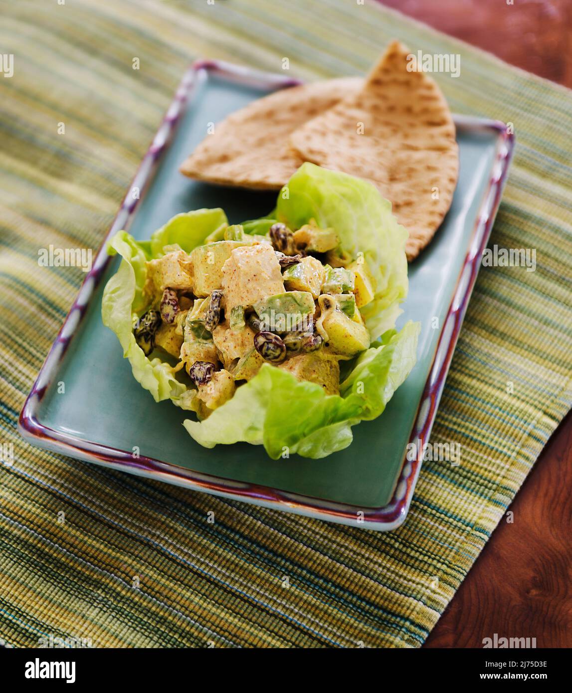 Hühnercury mit Rosinen, Apfel und Sellerie in einem Salatblatt serviert mit ungesäuertem Brot (Indien) Stockfoto