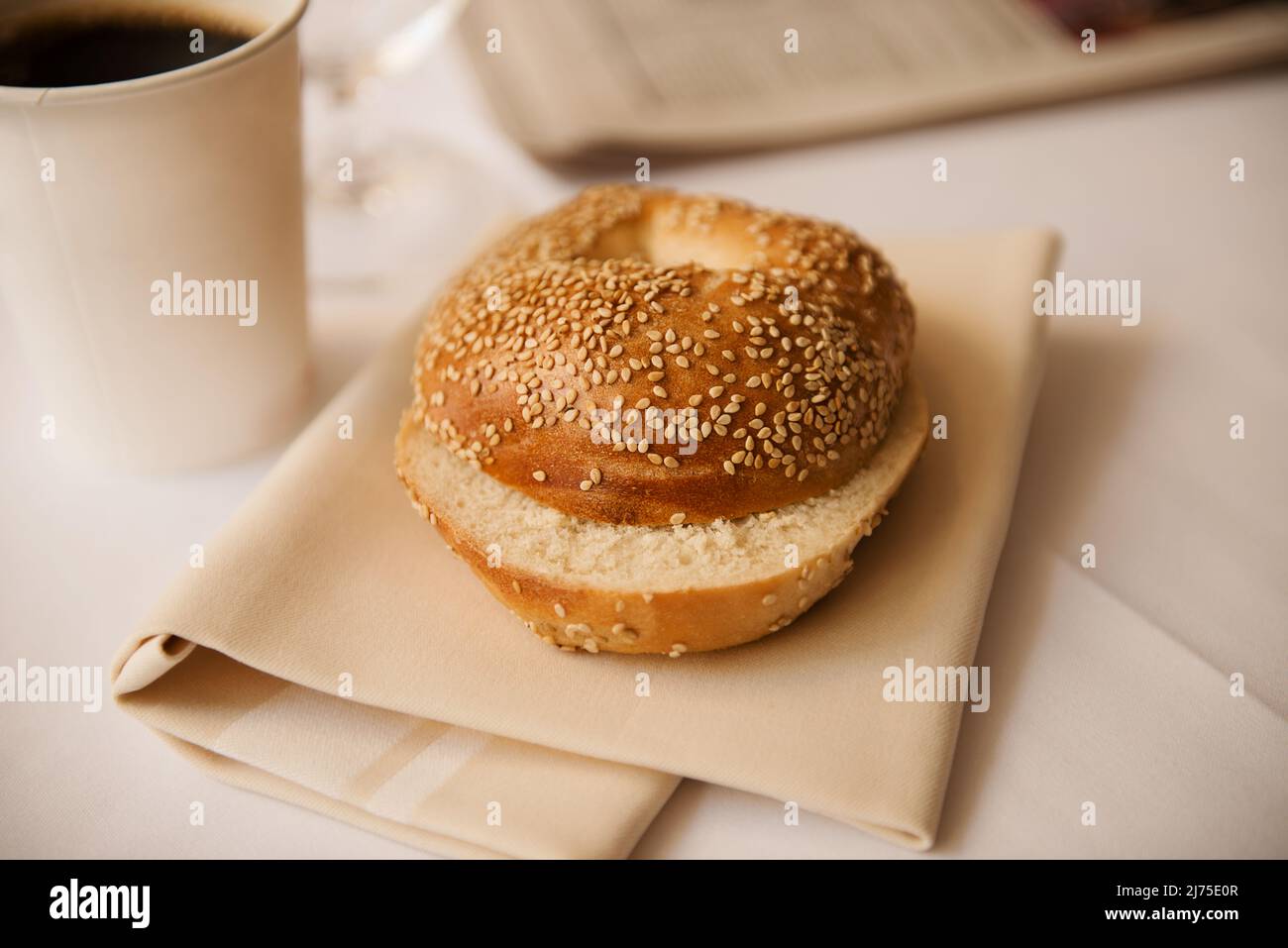 Ein Sesambagel mit einer Tasse Kaffee und einer Zeitung Stockfoto