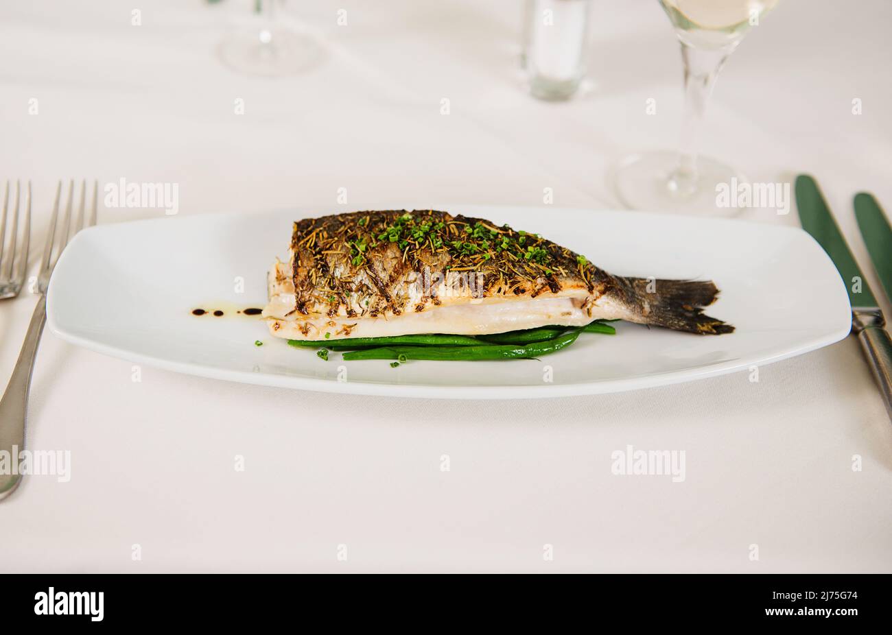 Gegrillter Fisch mit Herbes de Provence und frisch geschnittenem Schnittlauch Stockfoto