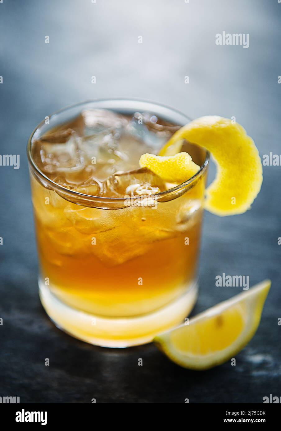 Eine Whiskey Sour mit Eiswürfeln, garniert mit Zitronenschale Stockfoto