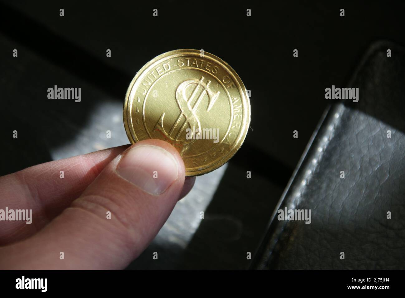 Die Hand hält eine goldene Dollar-Münze. Erfolgreiches Geschäft. Stockfoto