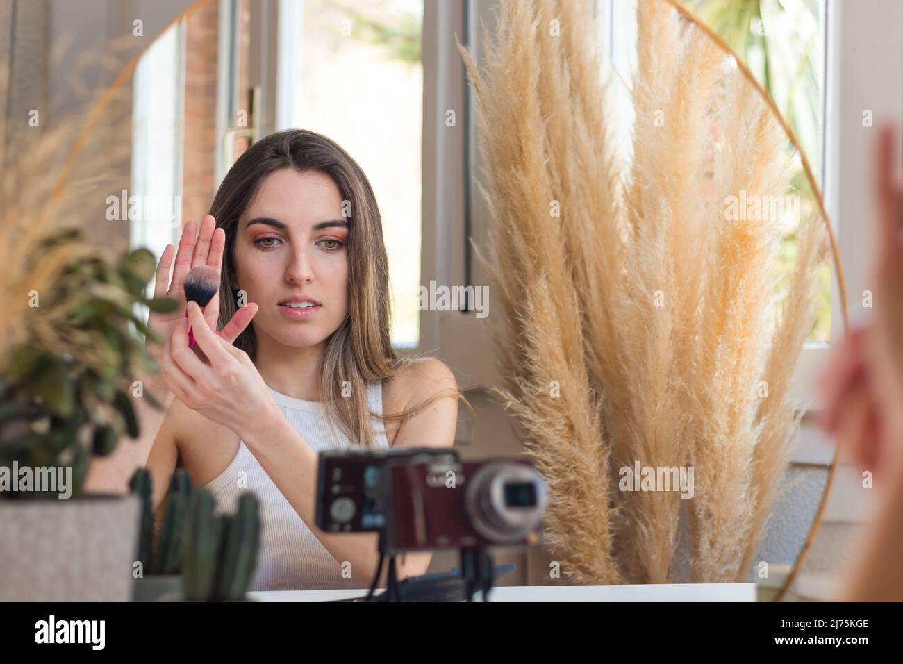 Schöne Frau Influencer vlogging auf Kamera zeigt ihre Lieblings Mekup Pinsel auf offener Hand Stockfoto