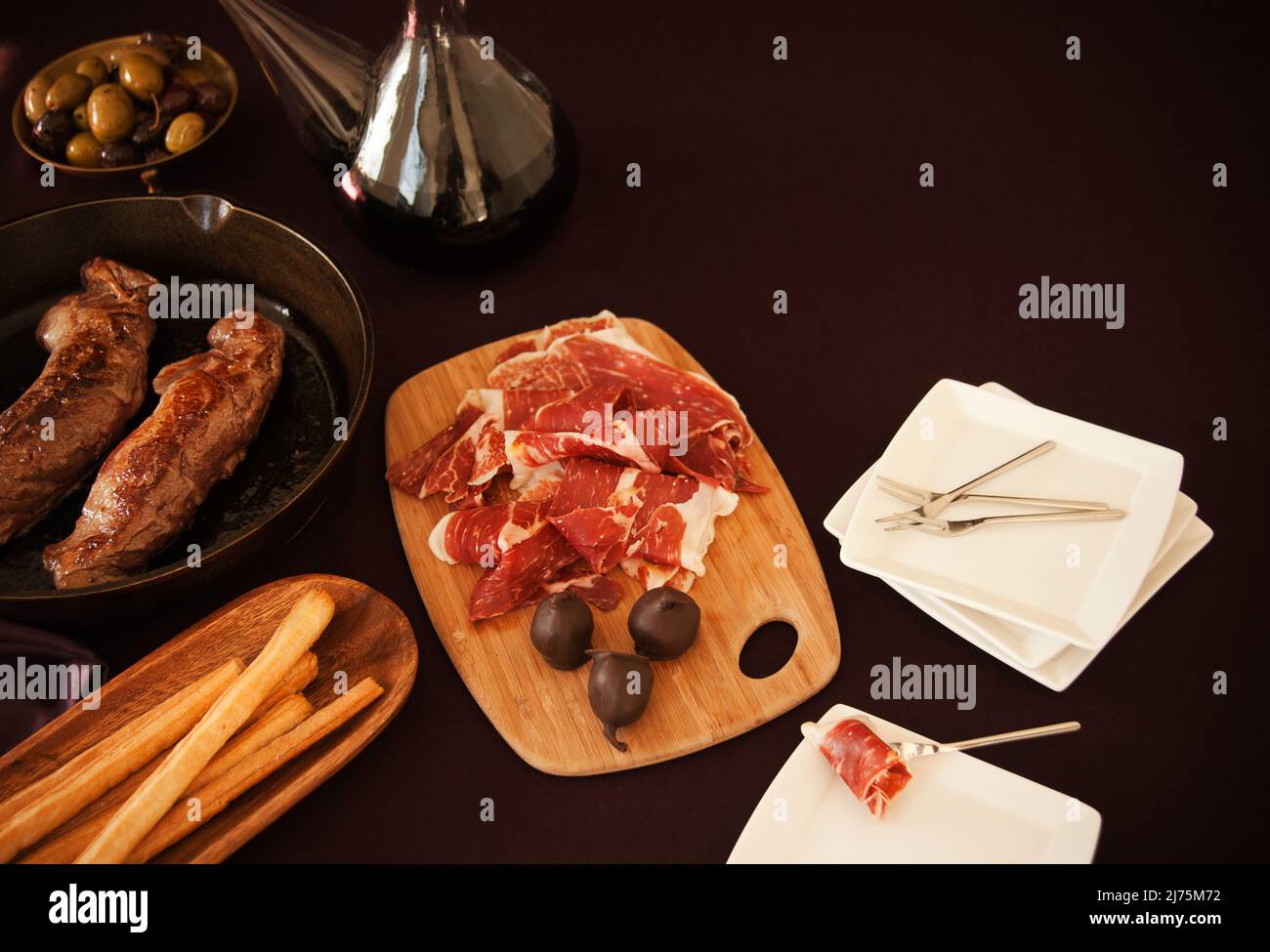 Spanische Mahlzeit von Jamon Iberico, Brotstangen, Oliven und mit Schokolade überzogene Feigen mit Rotwein Stockfoto