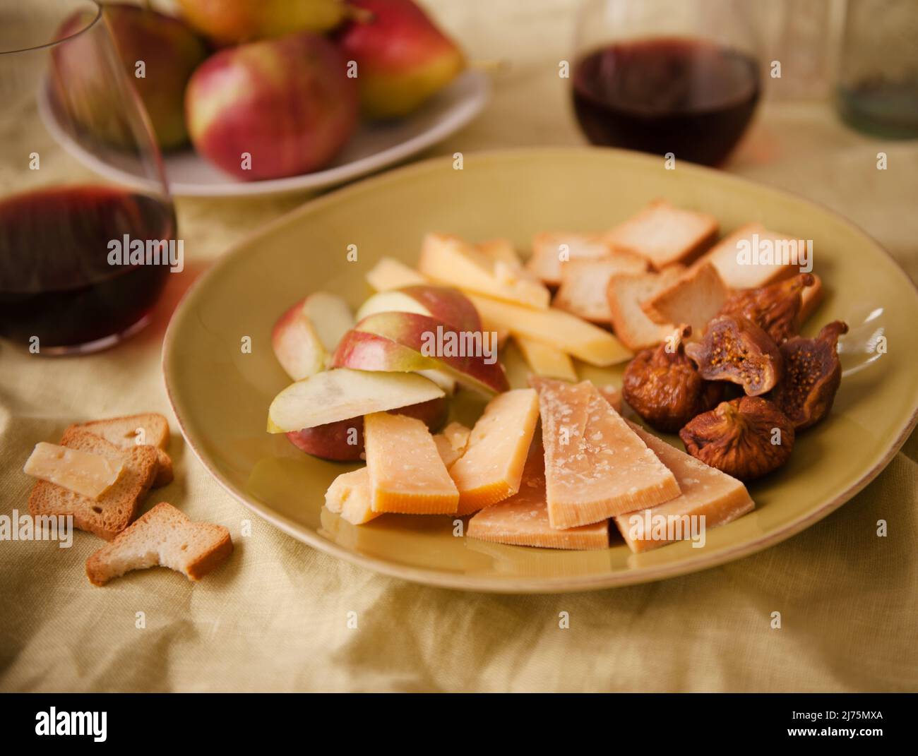 Gereifte Gouda-Scheiben, Apfelscheiben, Feigen und Cracker; mit Rotwein Stockfoto