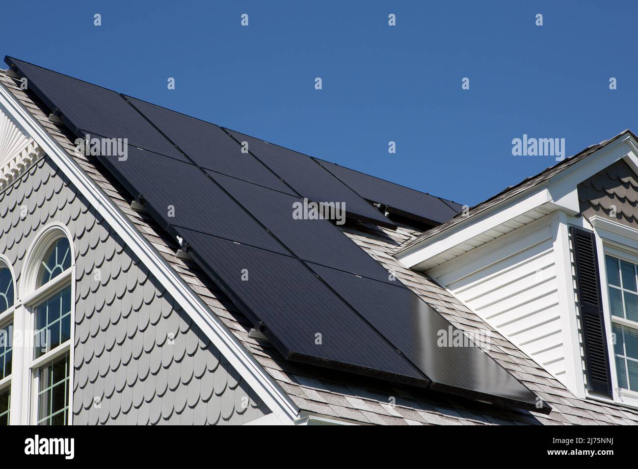 Solar-Panel-Installation auf einem schönen Cape Cod-Haus mit sonnigen blauen Himmel im Hintergrund Stockfoto