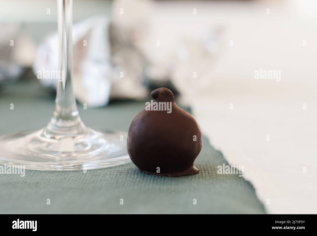 Eine mit Schokolade überzogene Feige neben einem Weinglas Stockfoto