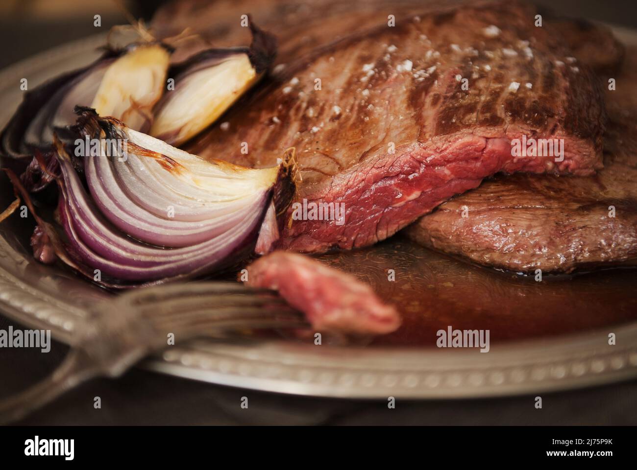 Rocksteak mit Zwiebeln; Steak selten gekocht; Stück auf einer Gabel durchbohrt Stockfoto