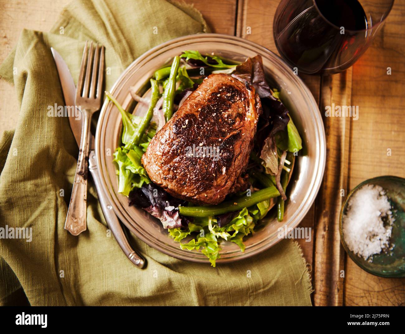 Sliced Grass Fed Sirloin Steak auf einem Bett mit Wein Stockfoto