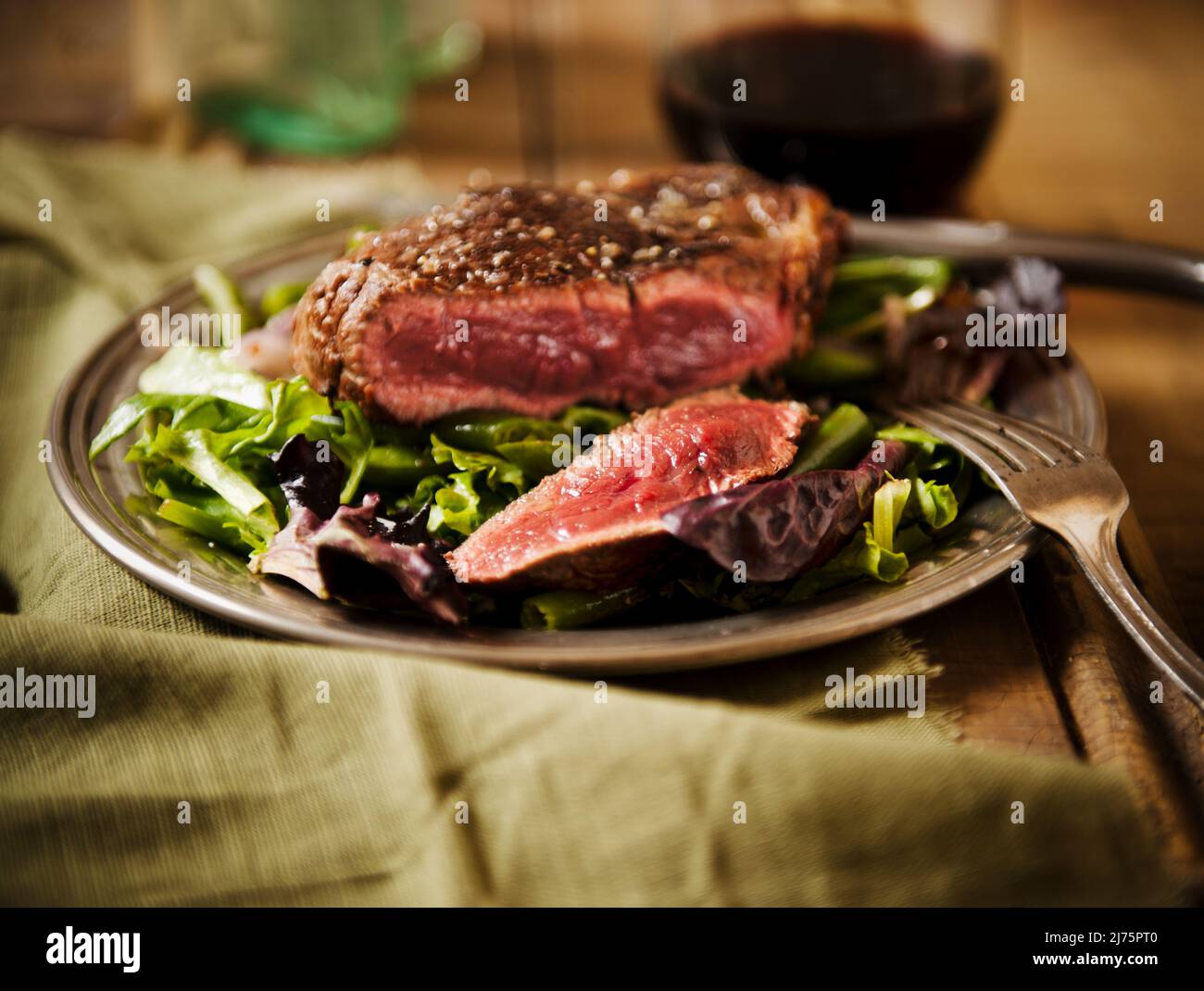 Sliced Grass Fed Sirloin Steak auf einem Bett mit Wein Stockfoto