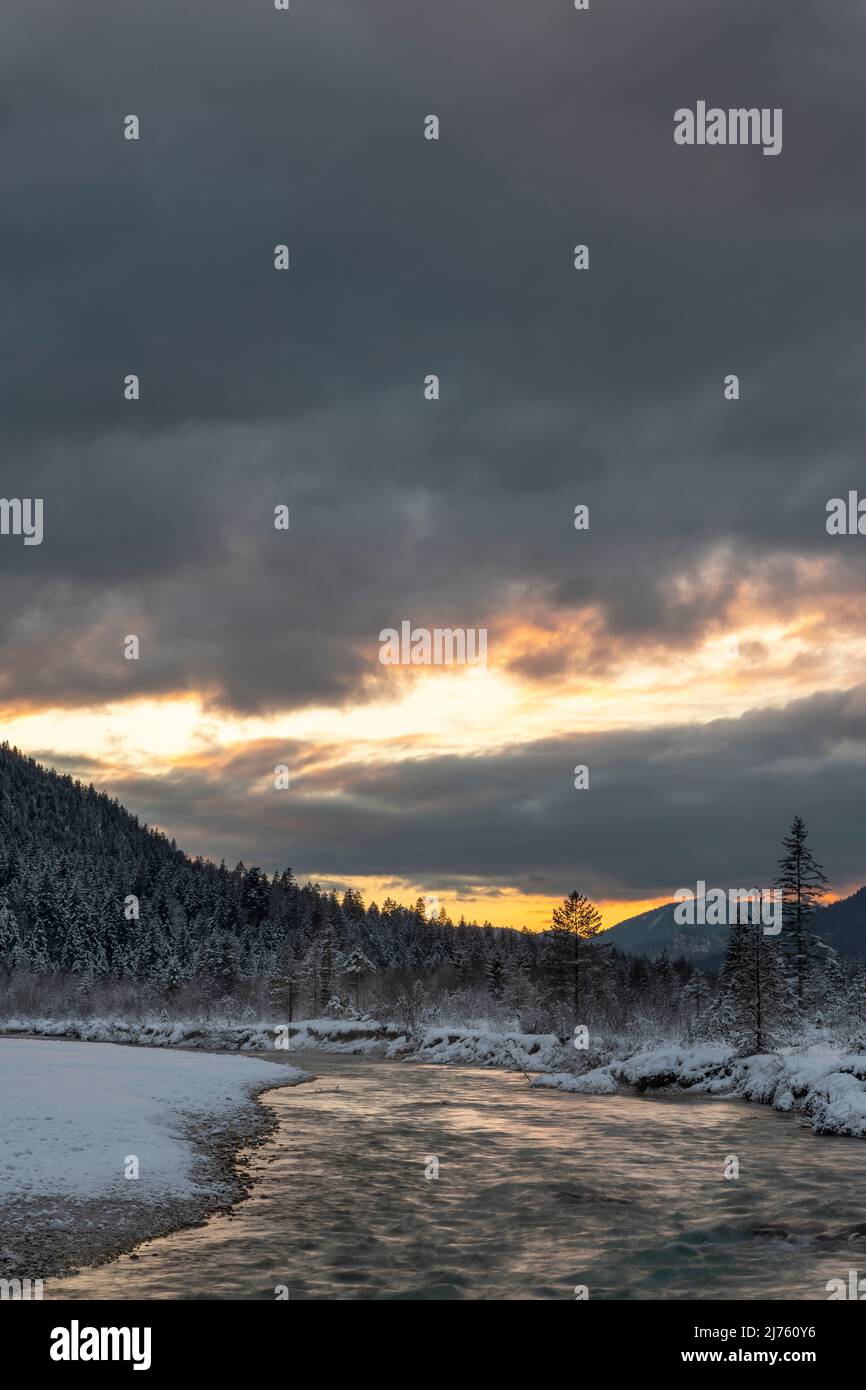 Dichte Wolken bei Sonnenuntergang in den Isarwiesen bei Wallgau im Karwendel, mit dem Bachbett / Flusslauf im Vordergrund Stockfoto