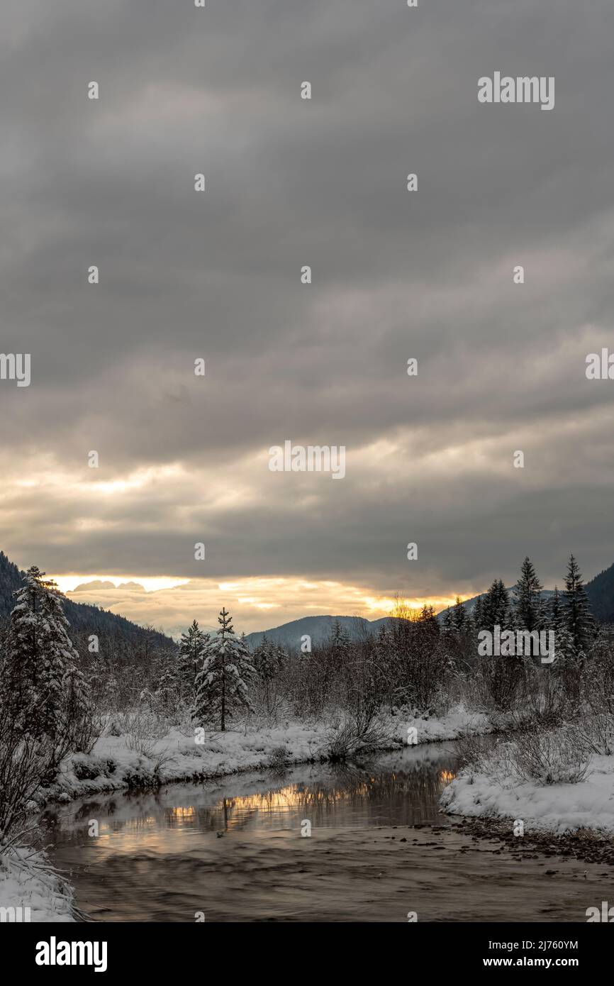 Dichte Wolken bei Sonnenuntergang in den Isarwiesen bei Wallgau im Karwendel, mit dem Bachbett / Flusslauf im Vordergrund Stockfoto