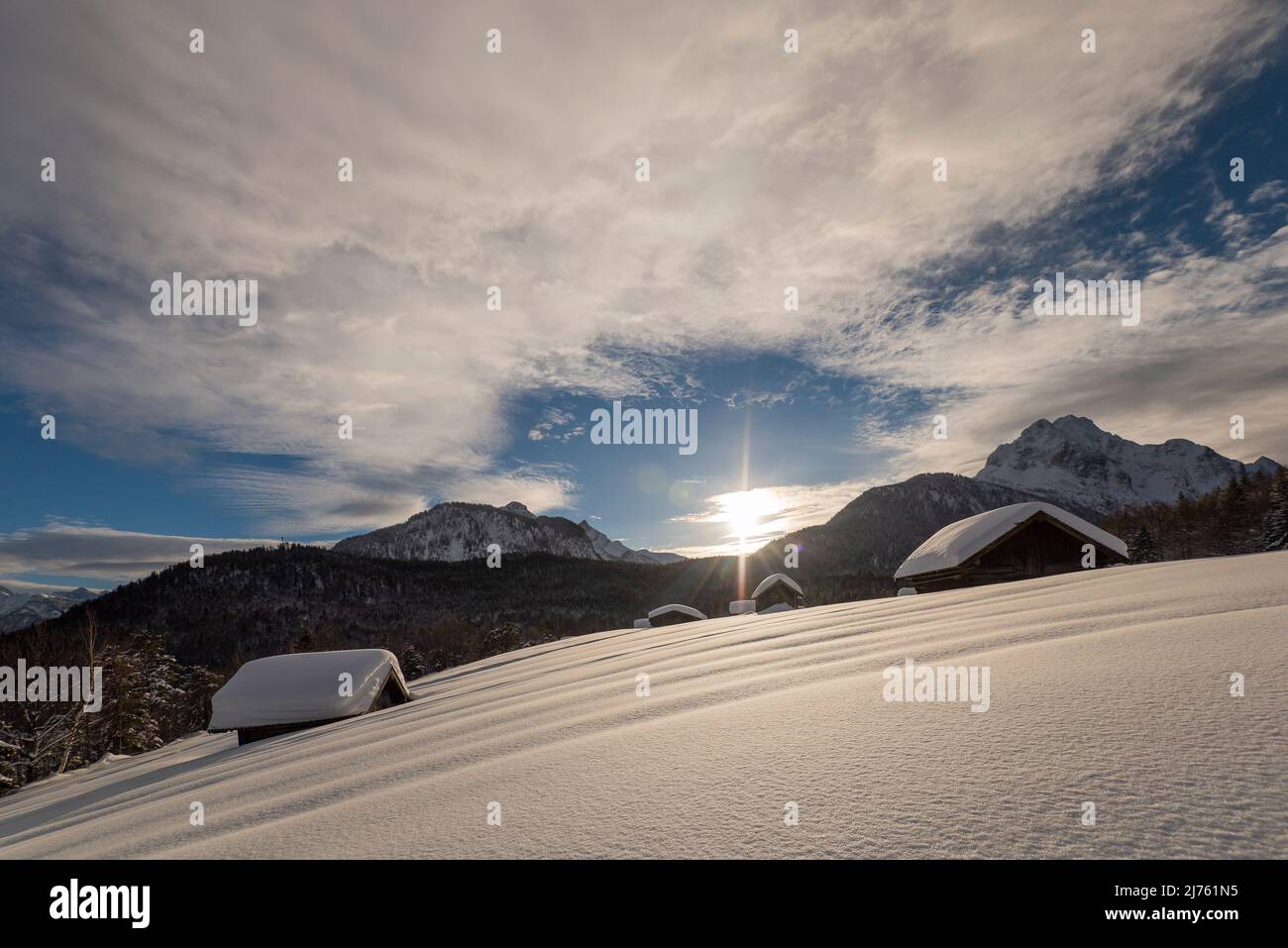 Sonnenstern auf dem Kaffeefeld oberhalb von Mittenwald in den bayerischen Alpen im Tiefschnee mit Heuhaufen Stockfoto