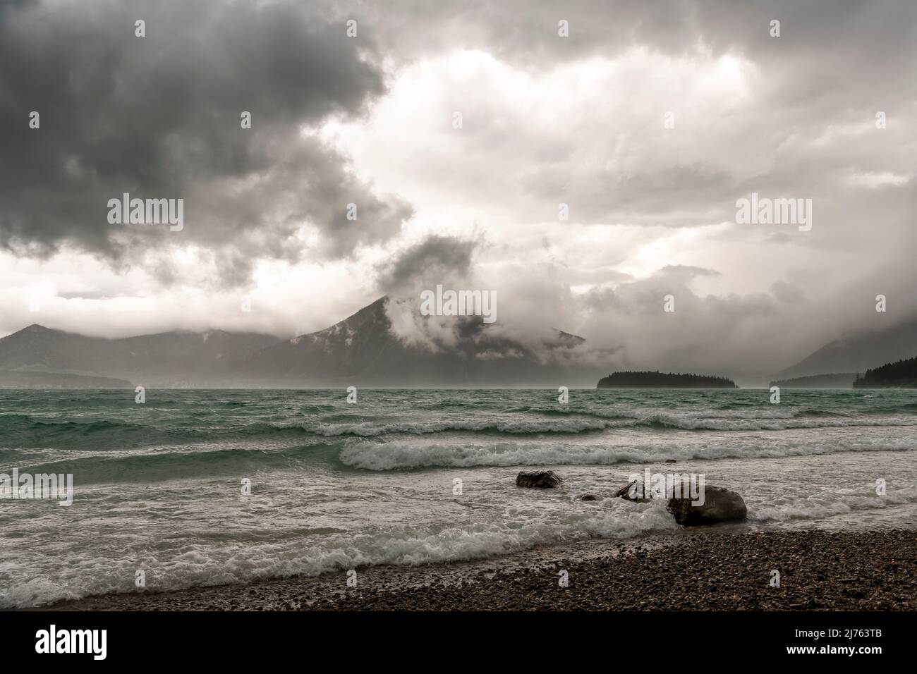 Ein gewaltiger Sturm mit Wellen, Wind und Wolken am Walchensee in den bayerischen Alpen. Im Hintergrund die kleine Insel Sassau und der Herzogstand zwischen Wolken. Stockfoto