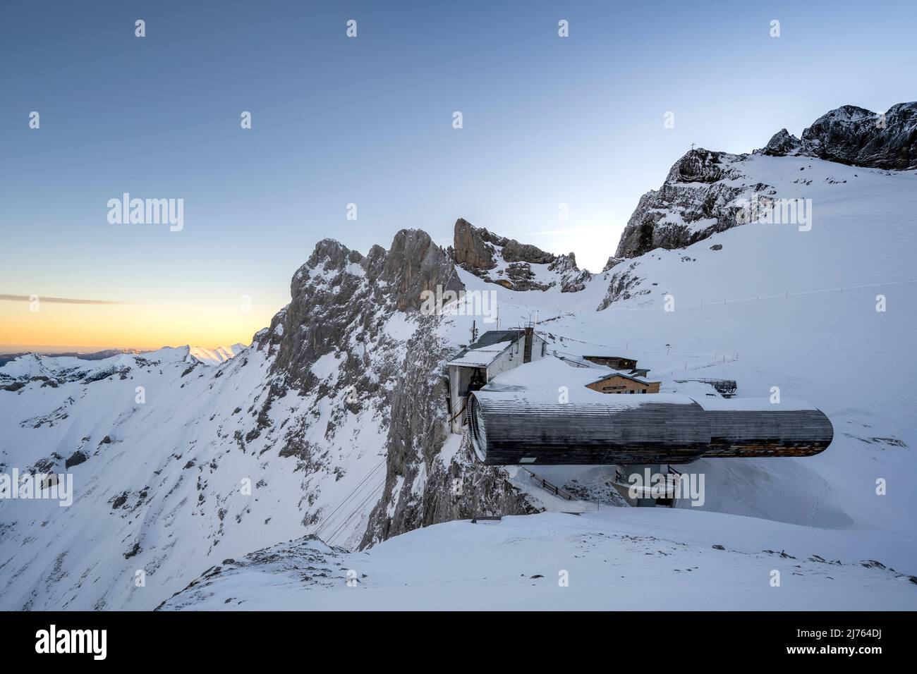 Das Teleskop, Museum an der Karwendelgrube an der Bergstation der Karwendelbahn in Mittenwald im Karwendel, im Winter mit Schnee, Eis und Sonnenaufgang. Die Karwendelköpfe oben und das Werdenfelser Land im Tal, die Struktur mit der Bergstation steht zwischen Fels und Schnee. Stockfoto