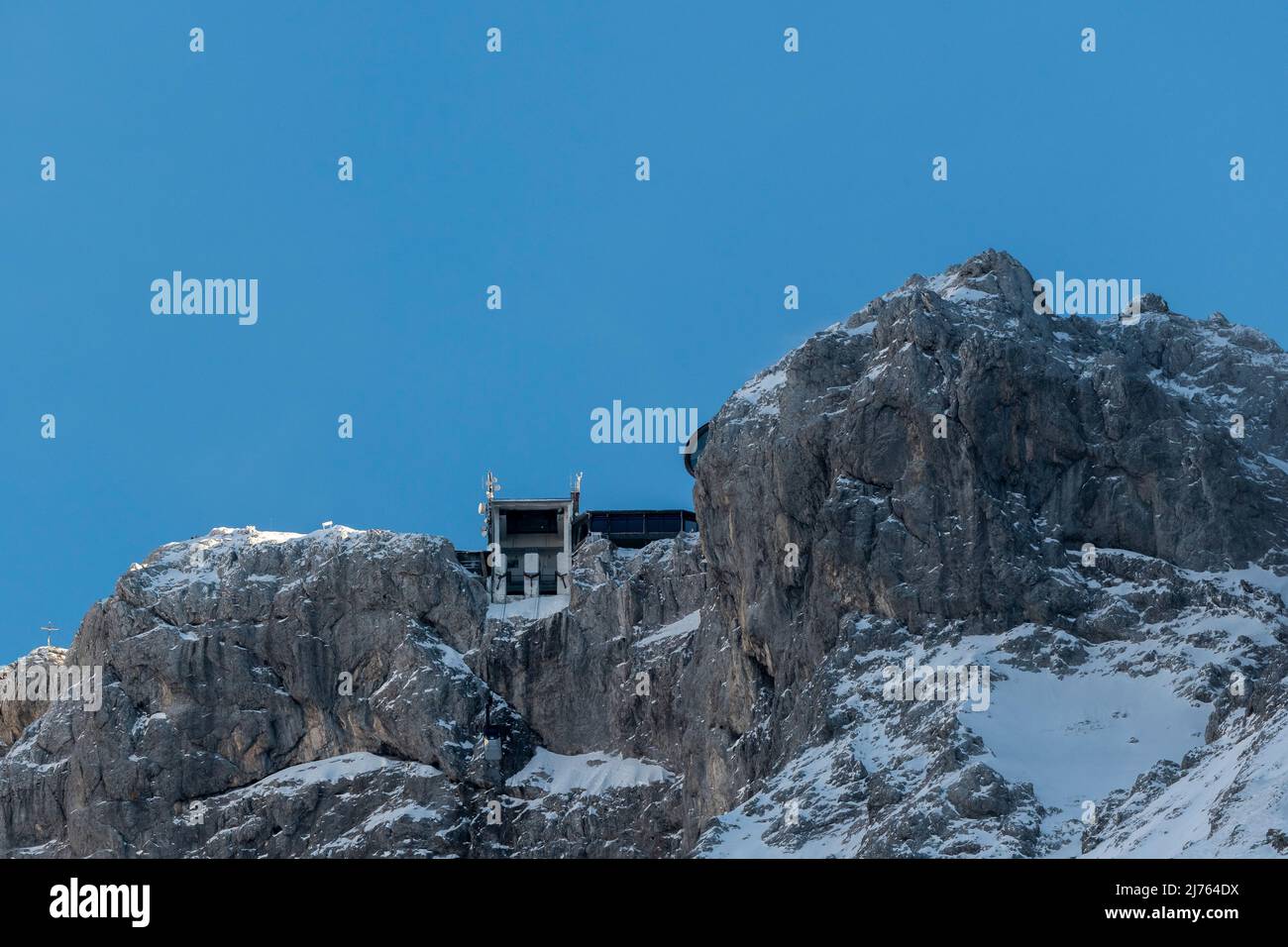 Die Bergstation der Karwendelbahn im Winter mit Schnee, Eis und harten Felsen. Eine Hütte auf dem Weg zum Gebäude. Stockfoto
