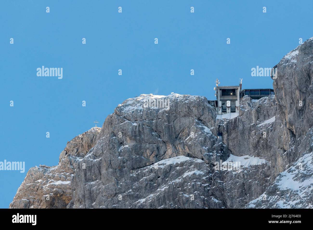 Die Bergstation der Karwendelbahn im Winter mit Schnee, Eis und harten Felsen. Eine Hütte auf dem Weg zum Gebäude. Stockfoto