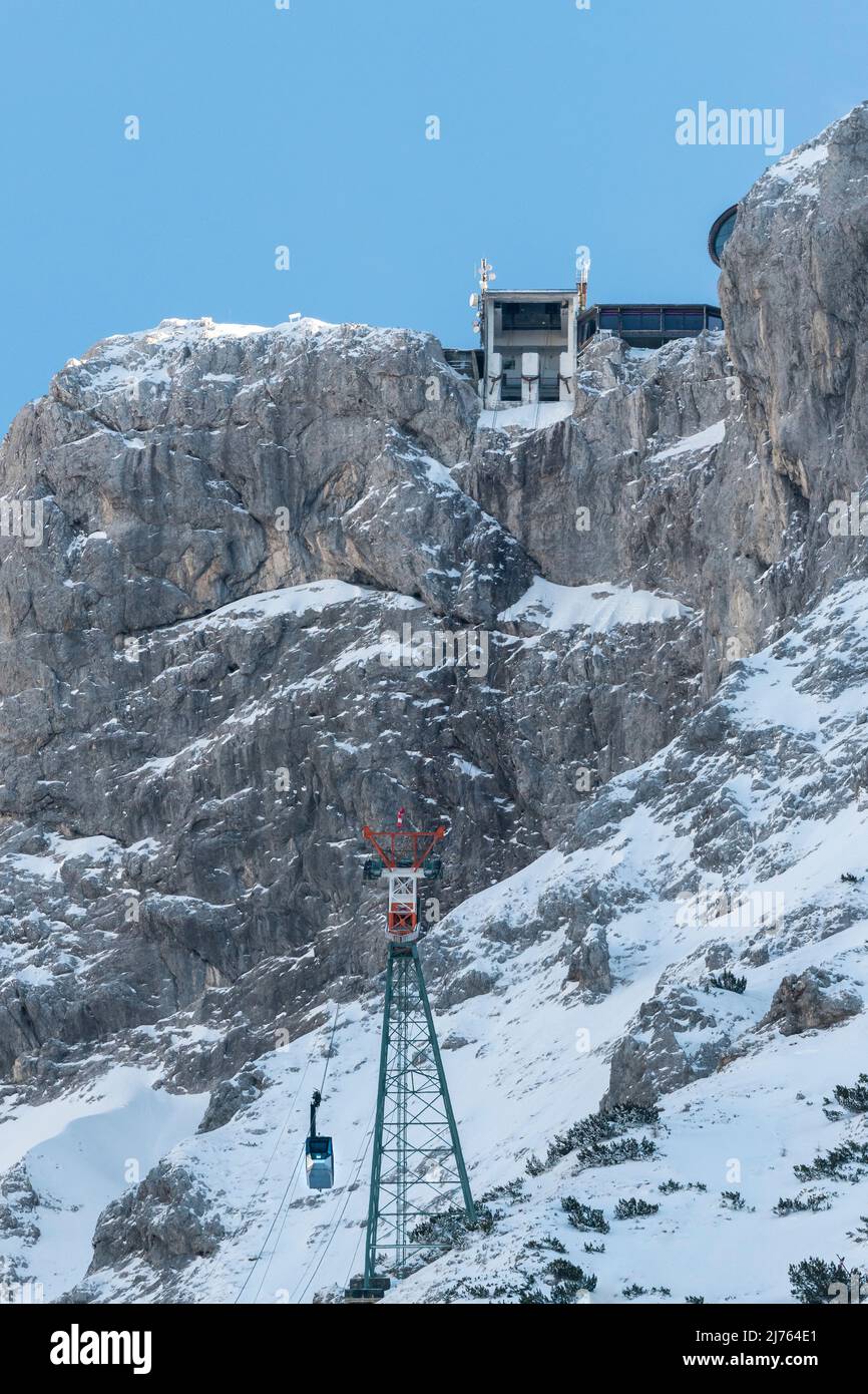 Die Bergstation der Karwendelbahn im Winter mit Schnee, Eis und harten Felsen. Eine Hütte auf dem Weg zum Gebäude. Stockfoto