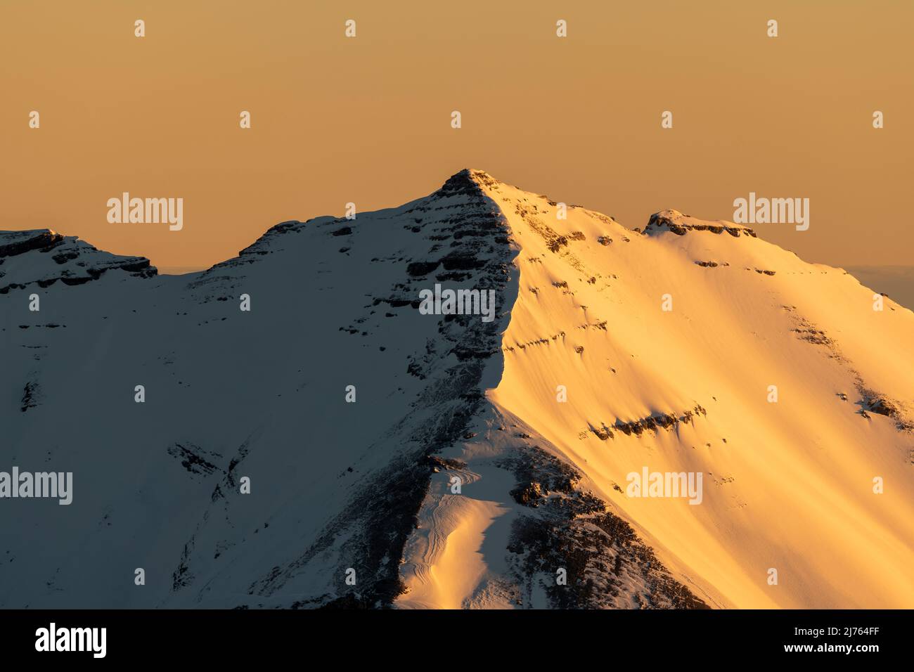 Die Soiernspitze erstrahlt bei Sonnenaufgang in goldenem, orangenen Licht. Aufgenommen im Winter mit Schnee und Eis von der westlichen Karwendelspitze oberhalb von Mittenwald. Stockfoto