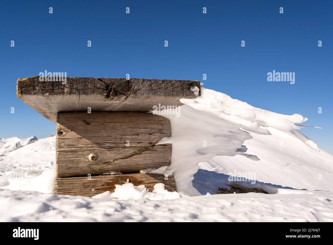 Eine Bank an der Bergstation der Karwendelbahn am Westkarwendel, in Schnee und Eis, mit bizarren Eiszapfen, die horizontal vom Sitz weg gehen. Stockfoto