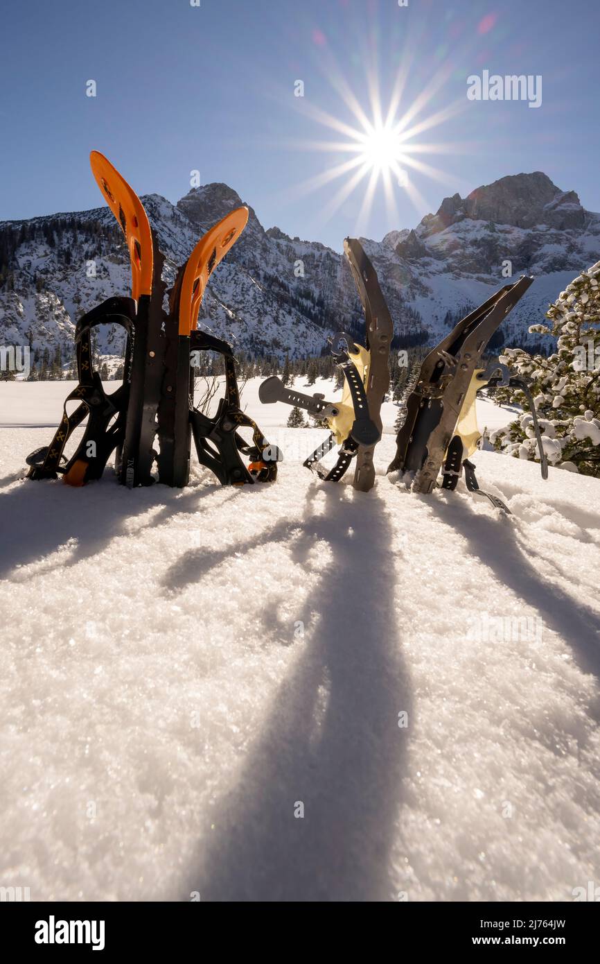 Zwei Paar Schneeschuhe stecken während einer Schneeschuhwanderung im Schnee fest, die Sonne mit einem perfekten Sonnenstern steht über dem Karwendel und erhellt die Winterlandschaft. Stockfoto