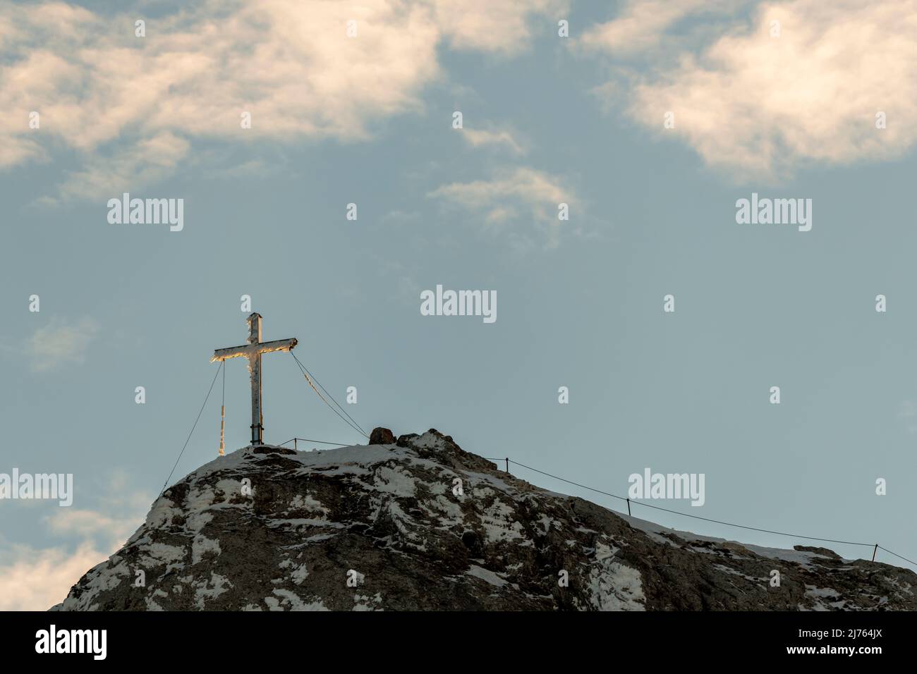 Das eingeschneite Gipfelkreuz der Westlichen Karwendelspitze im Karwendel oberhalb von Mittenwald, nahe der Bergstation der Karwendelbahn. Das Kreuz ist teilweise vereist, im Hintergrund der blaue Himmel. Stockfoto