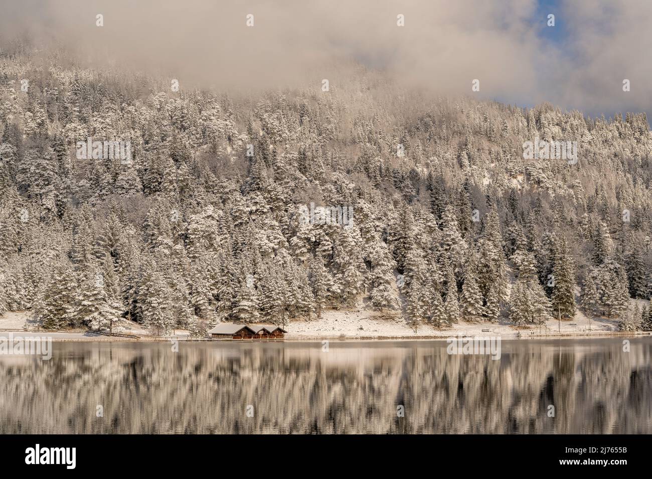 Die Bootshütte am Lautersee im Winter mit Schnee, Wolken und Nachmittagssonne mit Spiegelung im Wasser Stockfoto