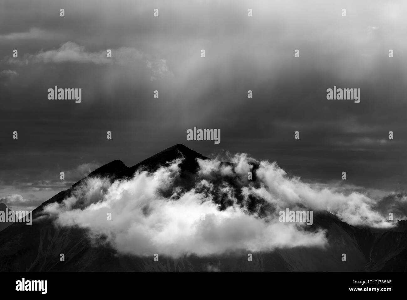Die Soiernspitze und Gruppe, fotografiert von der Mondscheinspitze wenige Kilometer entfernt. Eine kleine Wolke unter dem Gipfel, sowie Dunst und leichter Regen werden von der Dämmerung erleuchtet und bilden eine unwirkliche Lichtatmosphäre. Stockfoto
