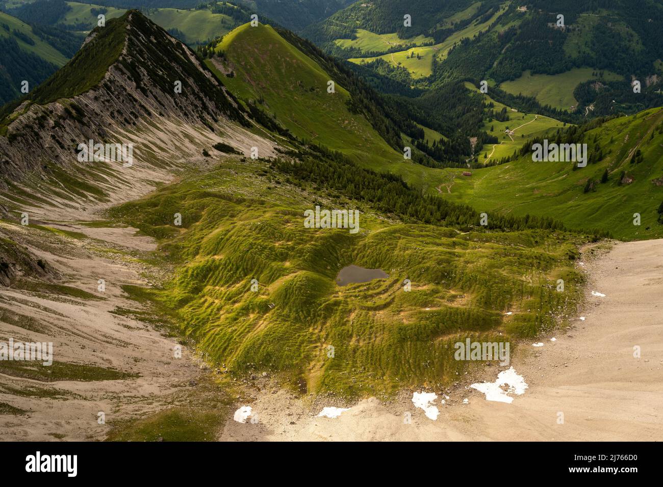 Kar unterhalb der Mondscheinspitze, auch Montscheinspitze geschrieben, im Karwendel. Ein kleiner Pool aus Wasser und Grünflächen bieten ein kleines gemütliches Tal ohne Bäume. Stockfoto